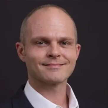 Man in suit with a dark background.